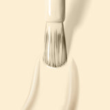 Close-up of a paintbrush applying LONDONTOWN's Buttercup onto a pale surface, with visible brush strokes. The subtle hint of pastel yellow creme adds a soft touch.