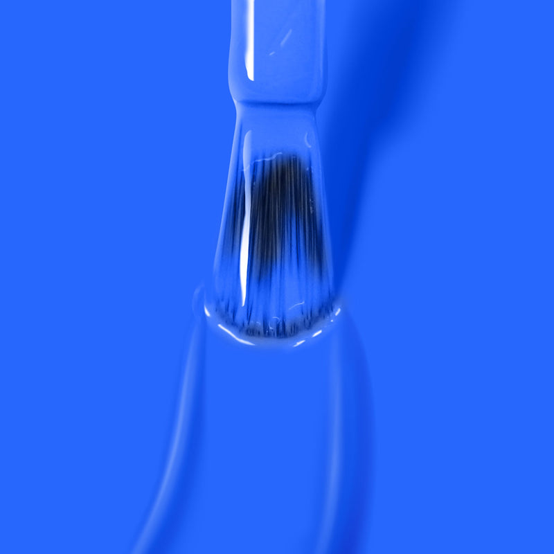 A paintbrush dipped in Iconic electric blue nail polish by LONDONTOWN against a blue background, reminiscent of the 2019 Allure Best of Beauty Award-winning vegan, cruelty-free products.